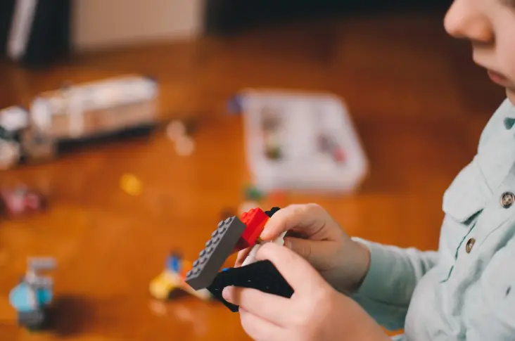 A kid playing and building with lego bricks