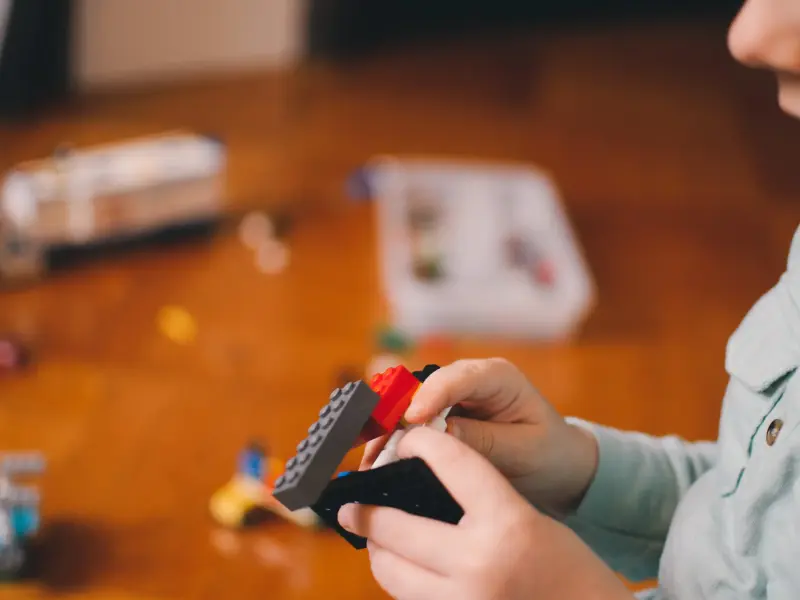 A kid playing and building with lego bricks